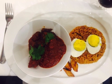 Nigerian Red Goat Stew, served with Jollof Rice, Plantain and Boiled Egg.